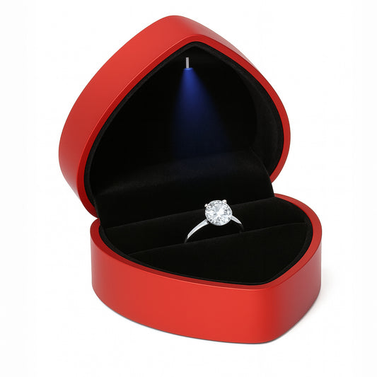 Open red heart shaped ring box with LED light holding engagement ring