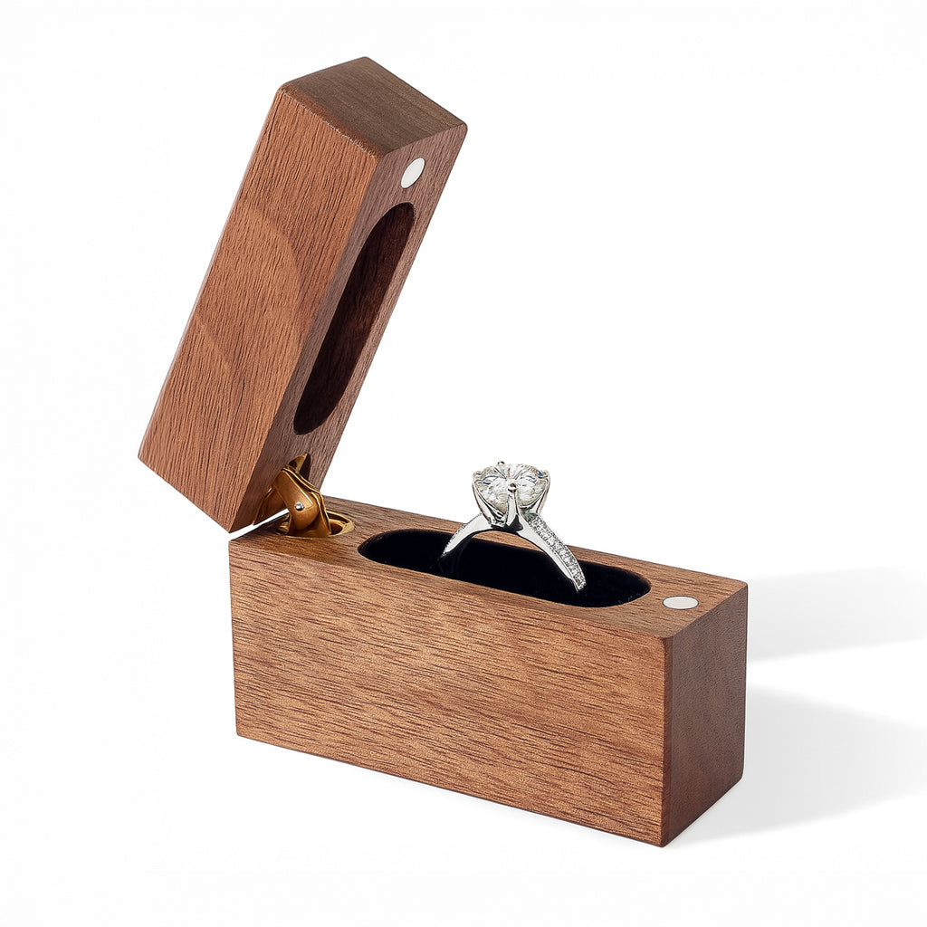 Open slim walnut wood ring box with black velvet interior holding engagement ring