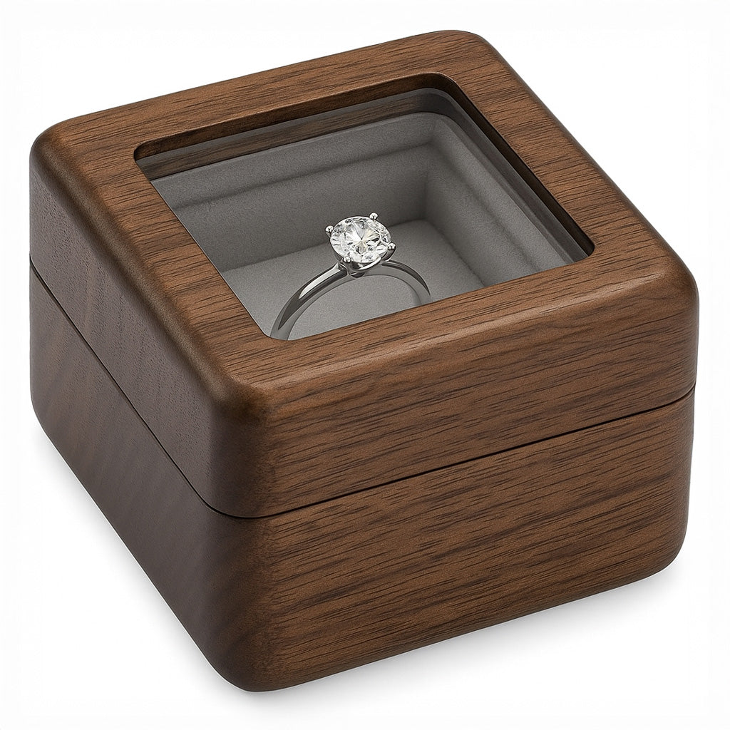 Closed walnut wood ring box with glass display lid showing engagement ring